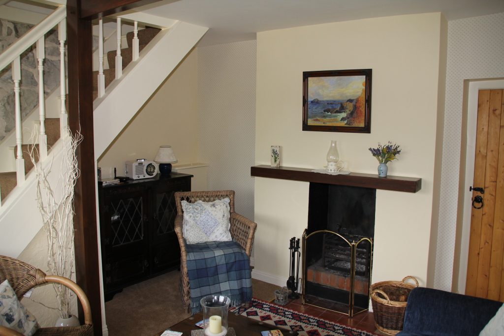 The lounge at Primrose Cottage with open fireplace and armchair